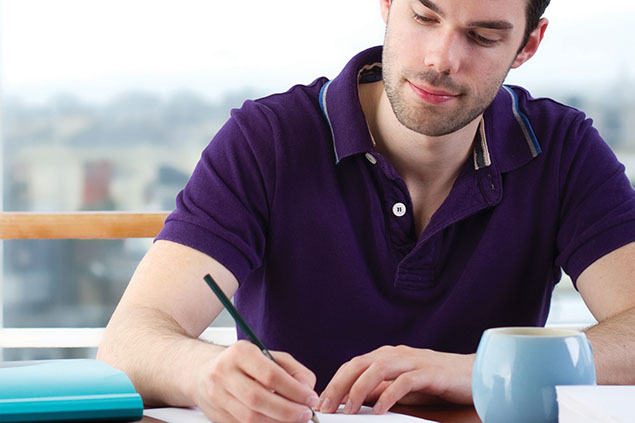 Image of young man writing in a journal.