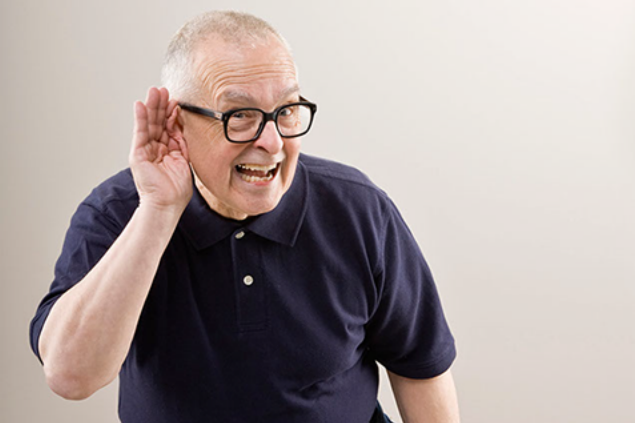 Image of older man holding hand around ear.
