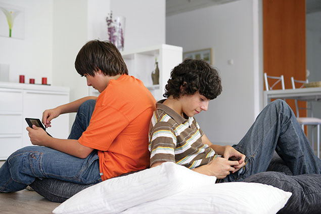 Image of two teenage boys on their cell phones.