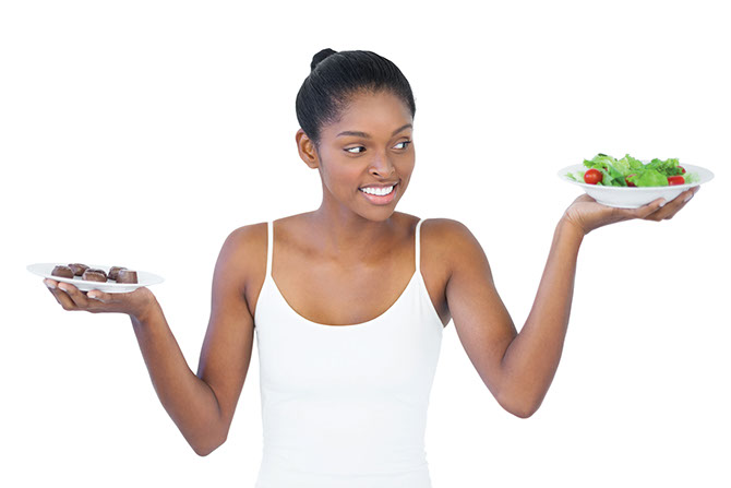Image of women holding a healthy salad in one hand and chocolate in the other.