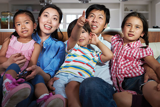 Image of family sitting on couch watching TV.