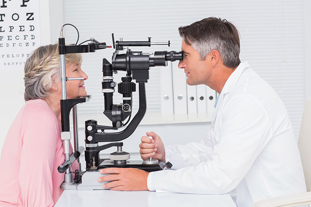 Image of older women getting her eyes check by an eye doctor.