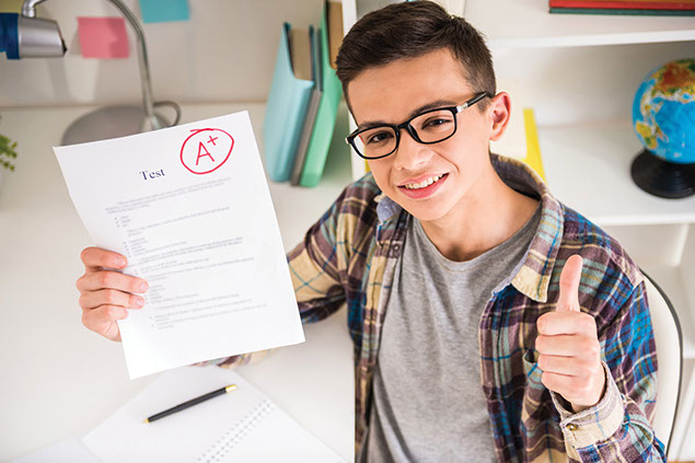 Image of kid holding an 'A' graded paper with thumbs up.