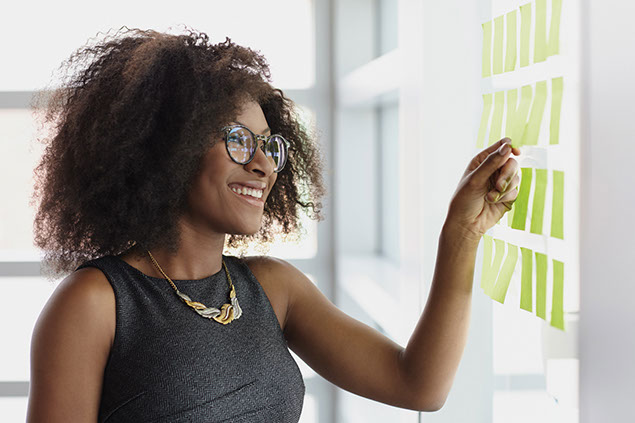 Image of women at work looking at notes posted on the wall.