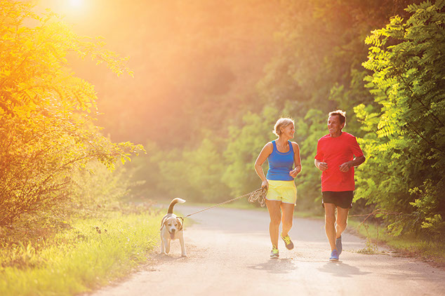 Image of older couple jogging with their dog.