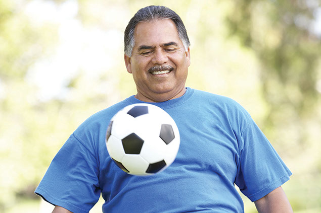Image of middle-aged Hispanic man playing with a soccer ball.