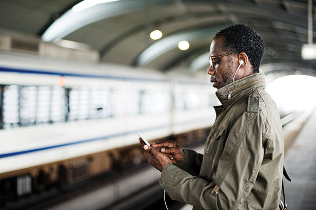 Image of man on phone while waiting at the subway.