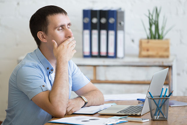 Image of man feeling sleepy at his desk.