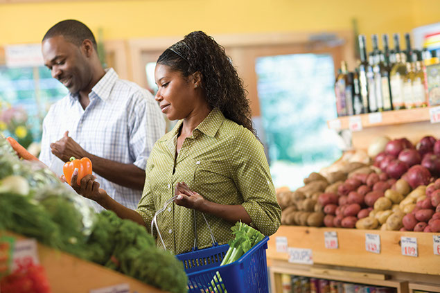 Image of couple at grocery store picking out peppers.