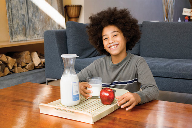 Image of boy with a glass of milk and an apple.