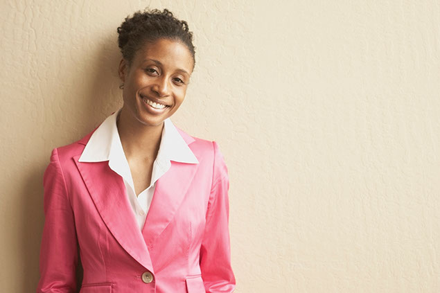 Image of middle-aged women smiling wearing a pink blazer.
