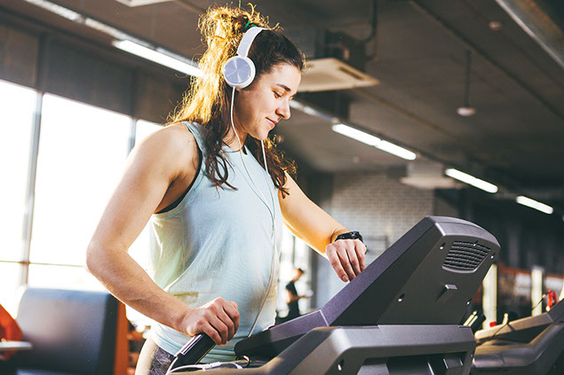 Women on treadmill looking at watch.