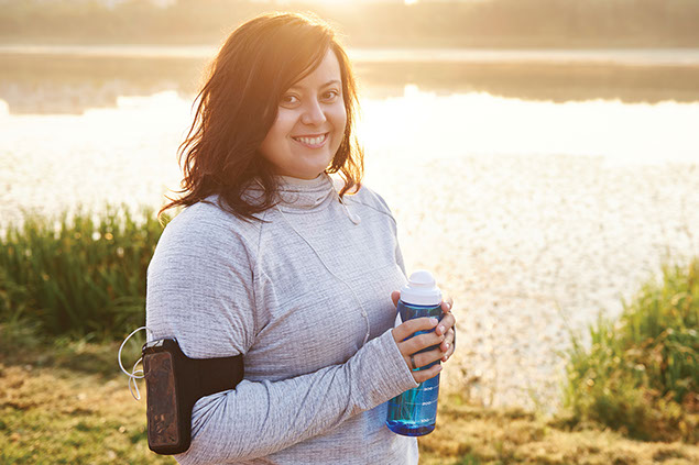Smiling women ready to exercise, holding a water bottle.
