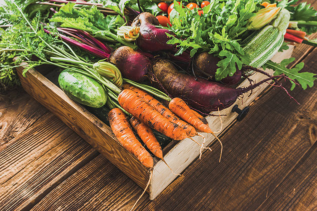 Variety of fresh produce in wooden box.