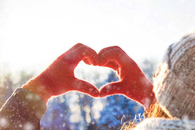 Winter image of hands wearing red gloves making a heart shape.