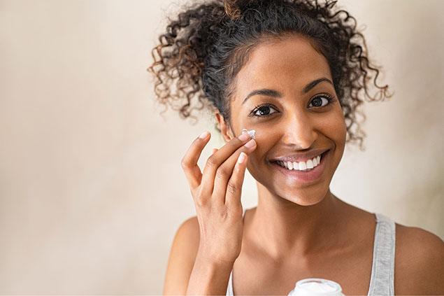 Female using face cream on cheeks.
