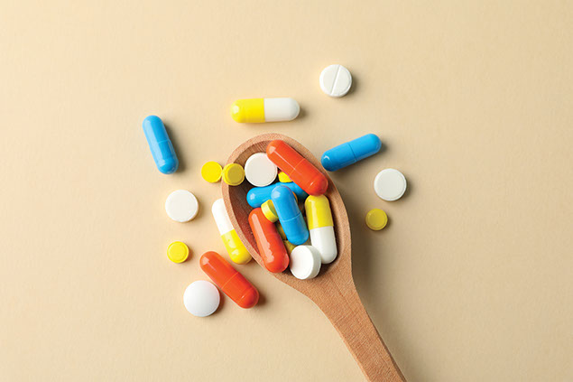 Wooden spoon filled with variety of pills.