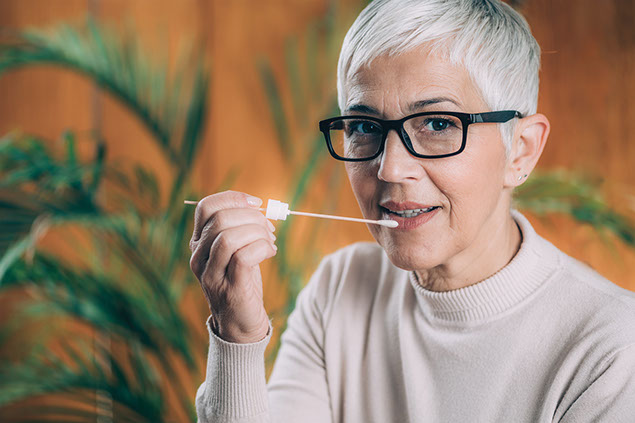 Women holding a swab near her mouth.