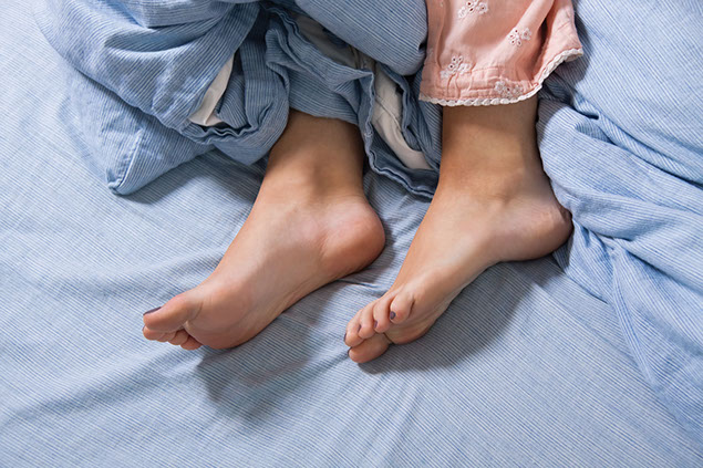 Close up feet laying in bed.