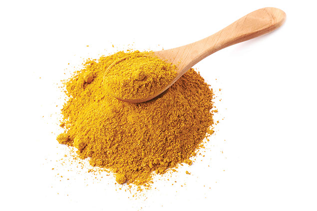 Curry powder and wooden spoon.