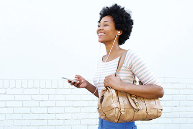 Women holding cell phone with head phones on.