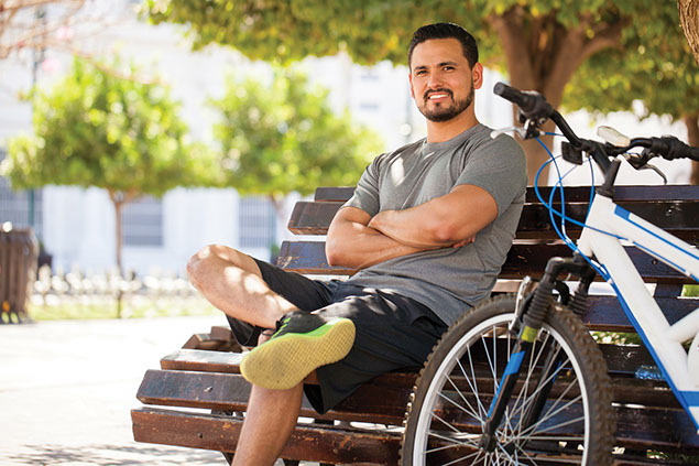 Man sitting on bench beside his bike.