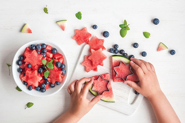 Kids hands cutting out star shaped watermelon.