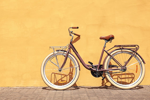 Bike up against a yellow wall.