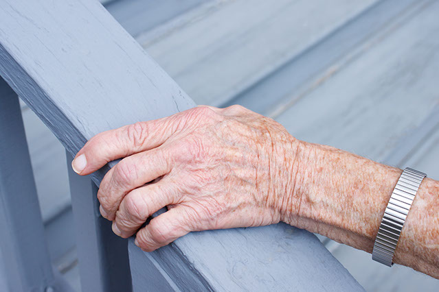 Image of an eldery hand holding onto rail.