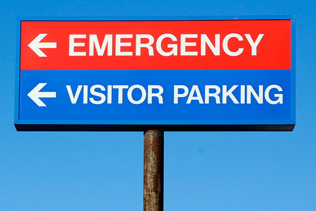 Image of a sign directing where the emergency room is and visitor parking.
