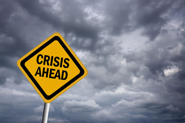 Image of dark skies with a road sign saying 'Crisis Ahead'.