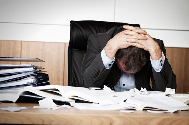 Image of man with head down at desk.