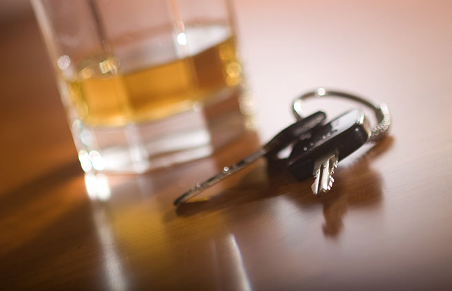 Image of keys and a glass of alcohol in the background.