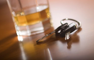Image of keys and a glass of alcohol in the background.
