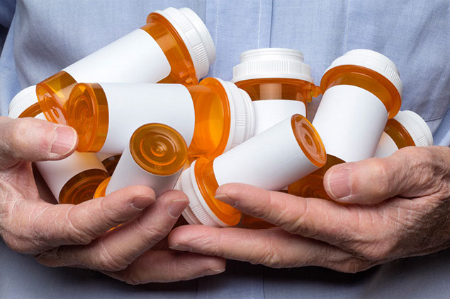 Image of older hands holding pill bottles.