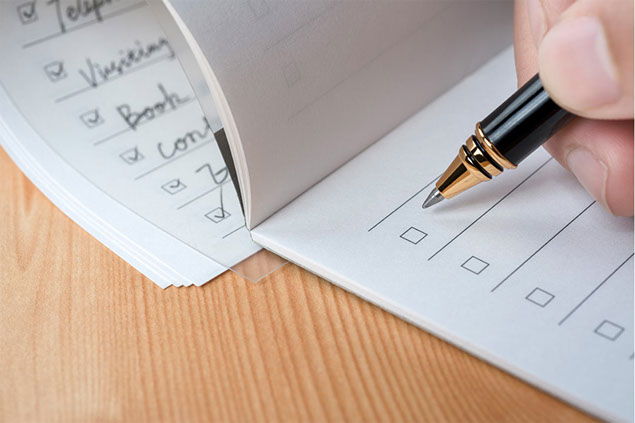 Close-up impage of pen and hand writing a checklist.