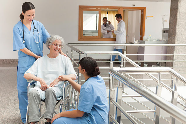 Image of women in wheel chair talking with two nurses.
