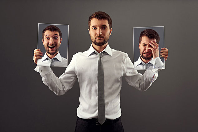 Image of man holding up images of different facial expressions.
