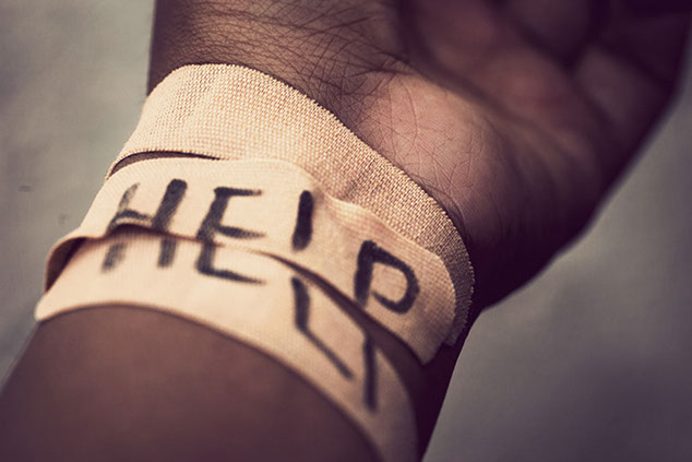 Close up image of wrist with bandage and the word Help.