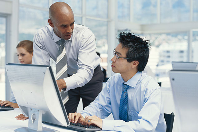 Image of workers talking next to computer.