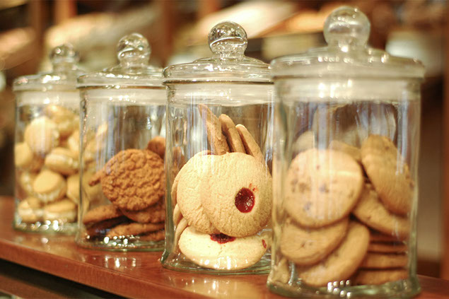 Image of cookie jars lined up with cookies in them.