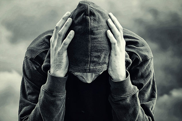 Image of man with his head down in hands.