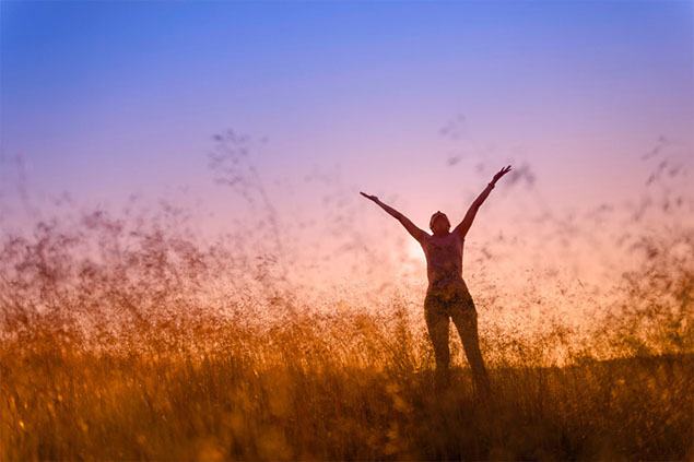 Image of happy person outside with arms up in the air.