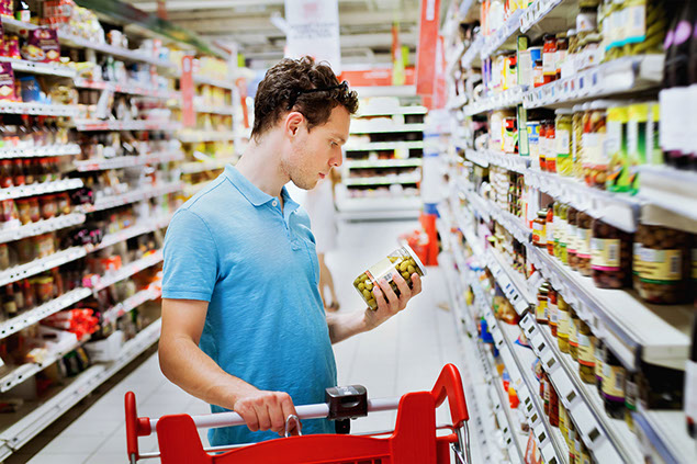 Image of man looking at nutrition label at the grocery store.