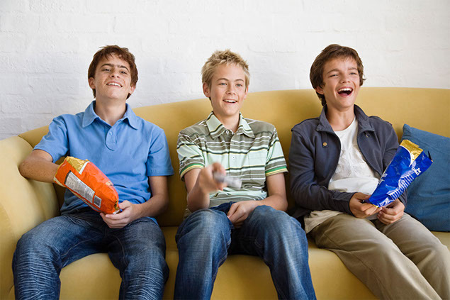 Image of teenage boys eating out of big bag of chips.