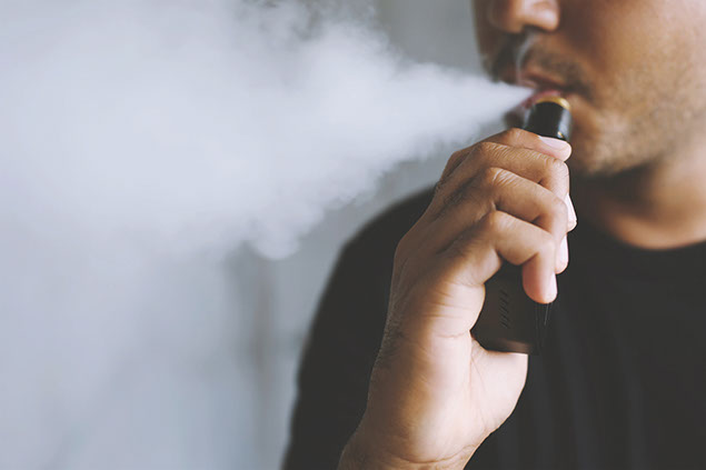 Man vaping and blowing smoke from his mouth.