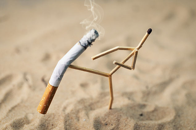 A stick figure made out of matches kicking a cigarette.