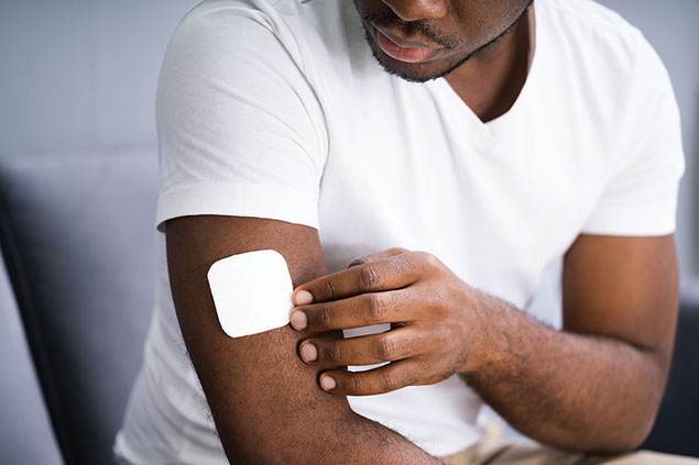 Man placing a nicotine patch on arm.