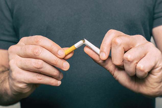 Close up of hands, breaking a cigarette in half.