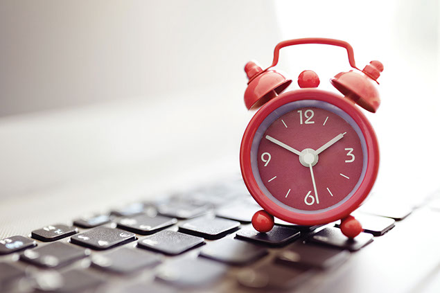Clock sitting on top of keyboard.